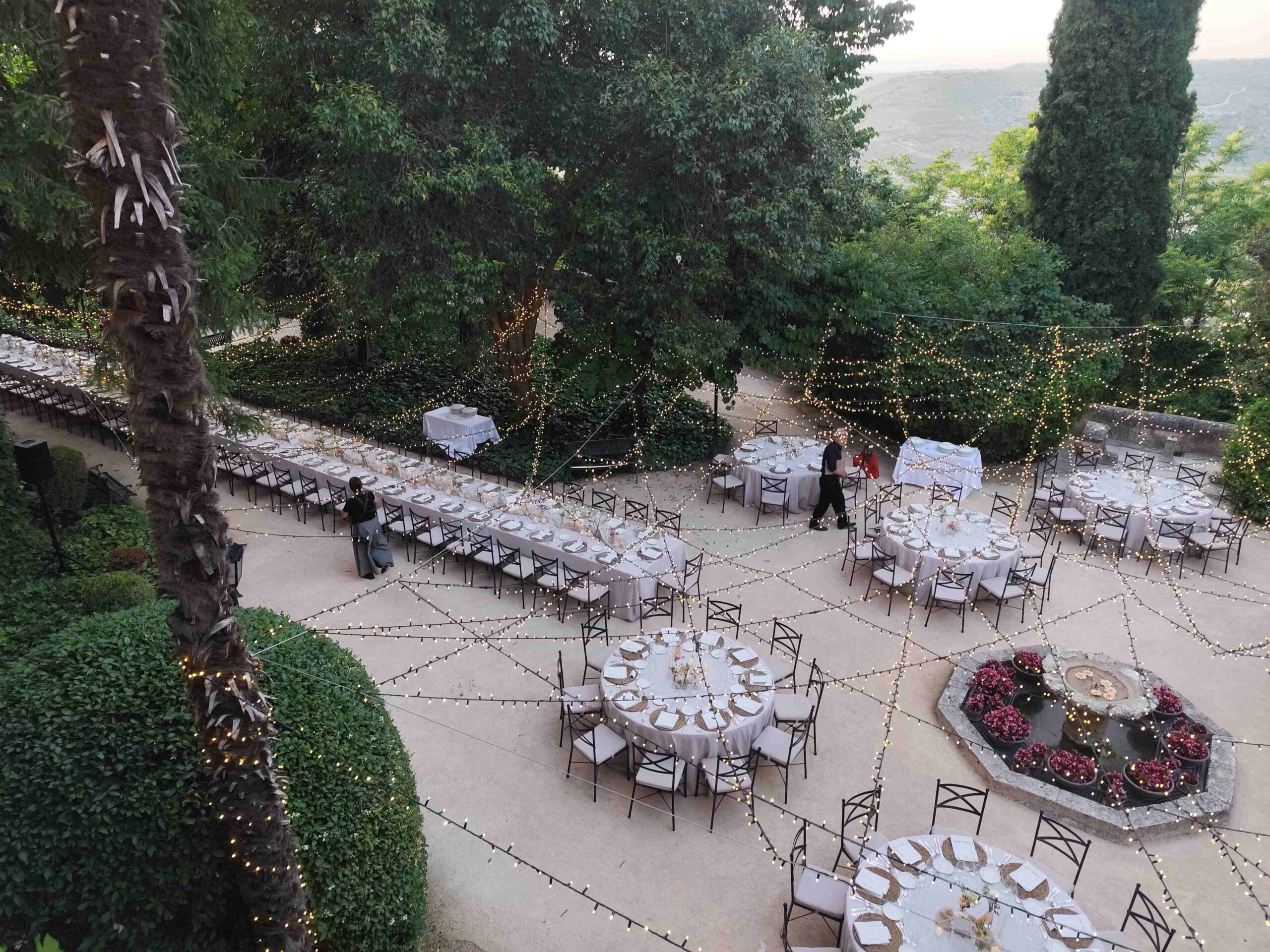 Banquete de boda al aire libre en los jardines del Monasterio de Lupiana con guirnaldas de luces